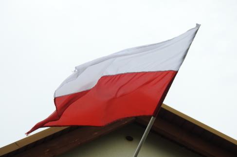 Polska flaga państwowa wywieszona przy szczycie domu mieszkalnego. 