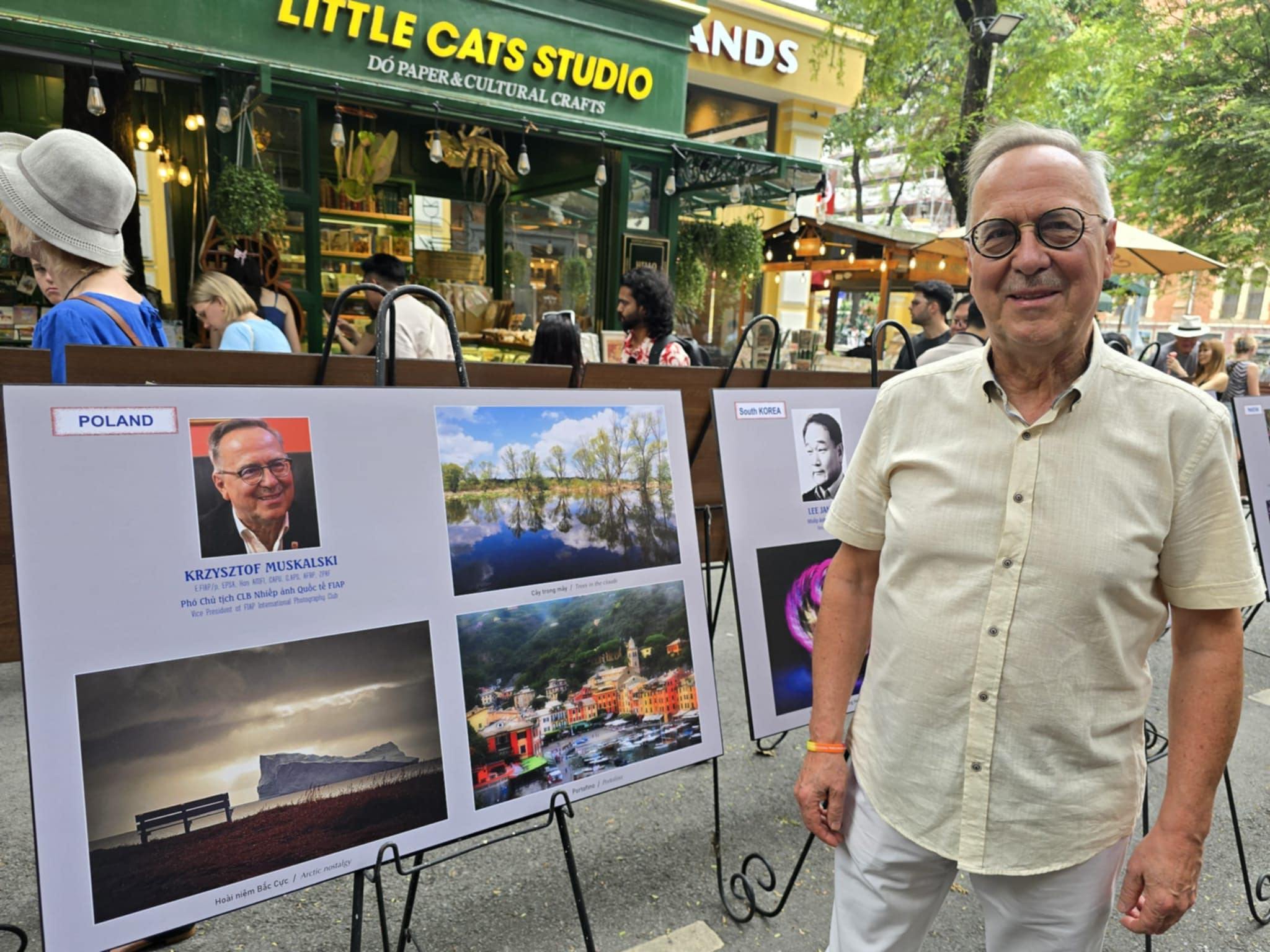Krzysztof Muskalski przy swoich fotografiach na wystawie w Wietnamie