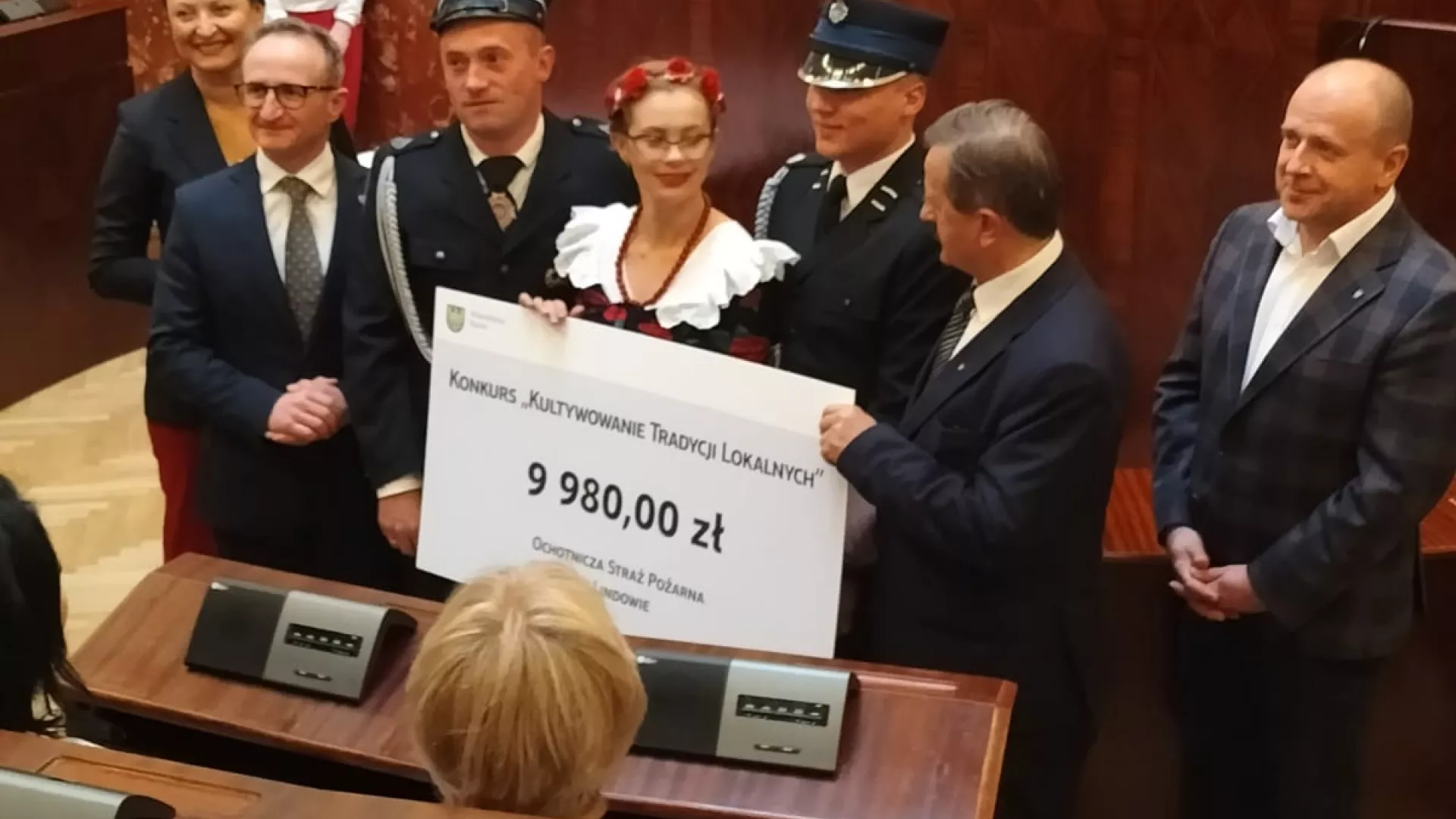 Delegacja OSP Lindów i KGW Stanisławów w sali plenarnej Sejmiku Województwa Śląskiego z czekiem symbolicznie poświadczającym otrzymanie dotacji.