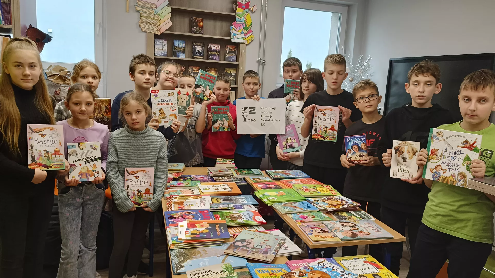 Klasa 5 podczas zajęć w bibliotece szkolnej z książkami nowo zakupionymi w ramach NPRCZ.