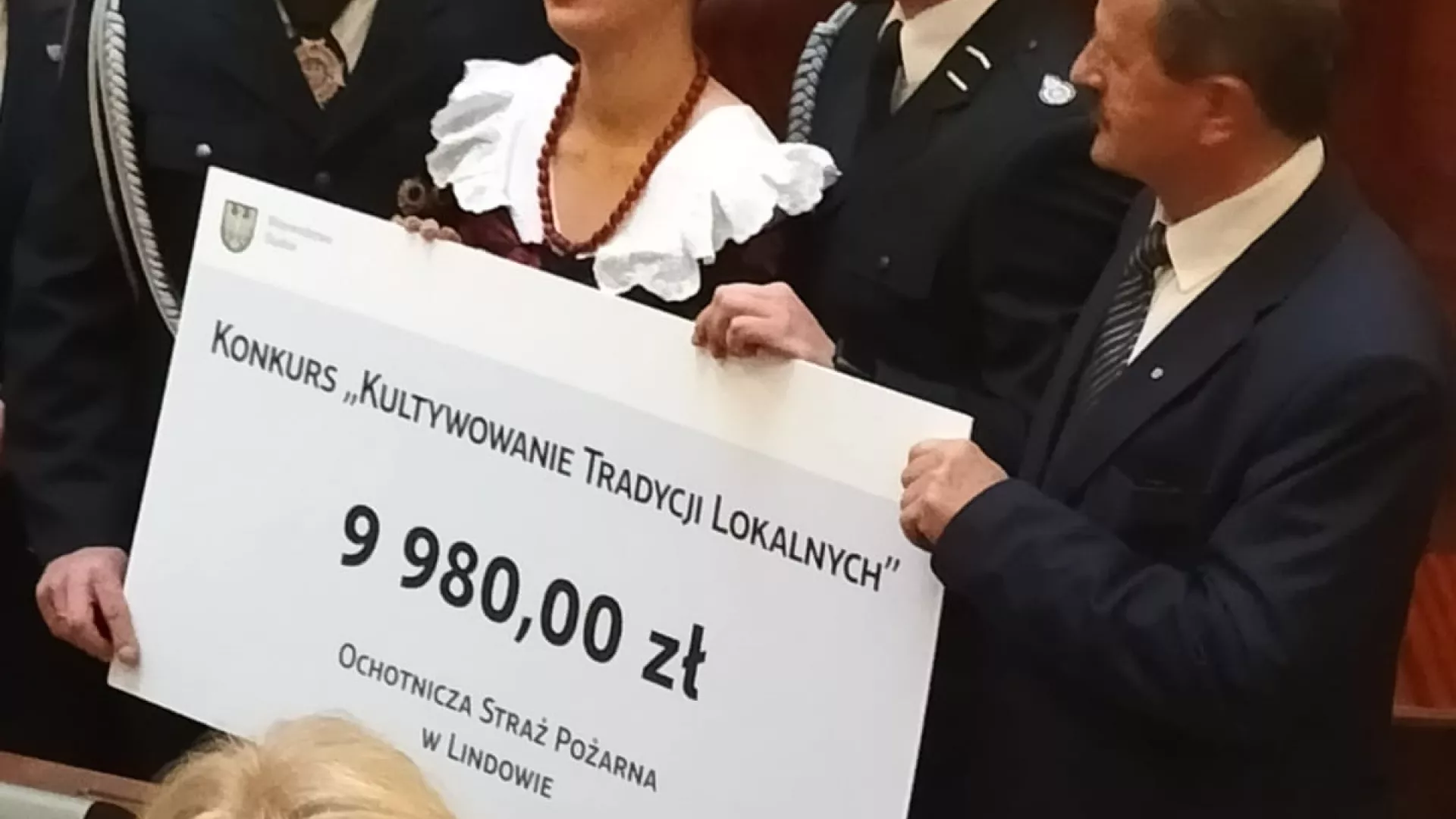Delegacja OSP Lindów i KGW Stanisławów wraz z wiceprzewodniczącym sejmiku Stanisławem Gmitrukiem trzymają symboliczny czek.
