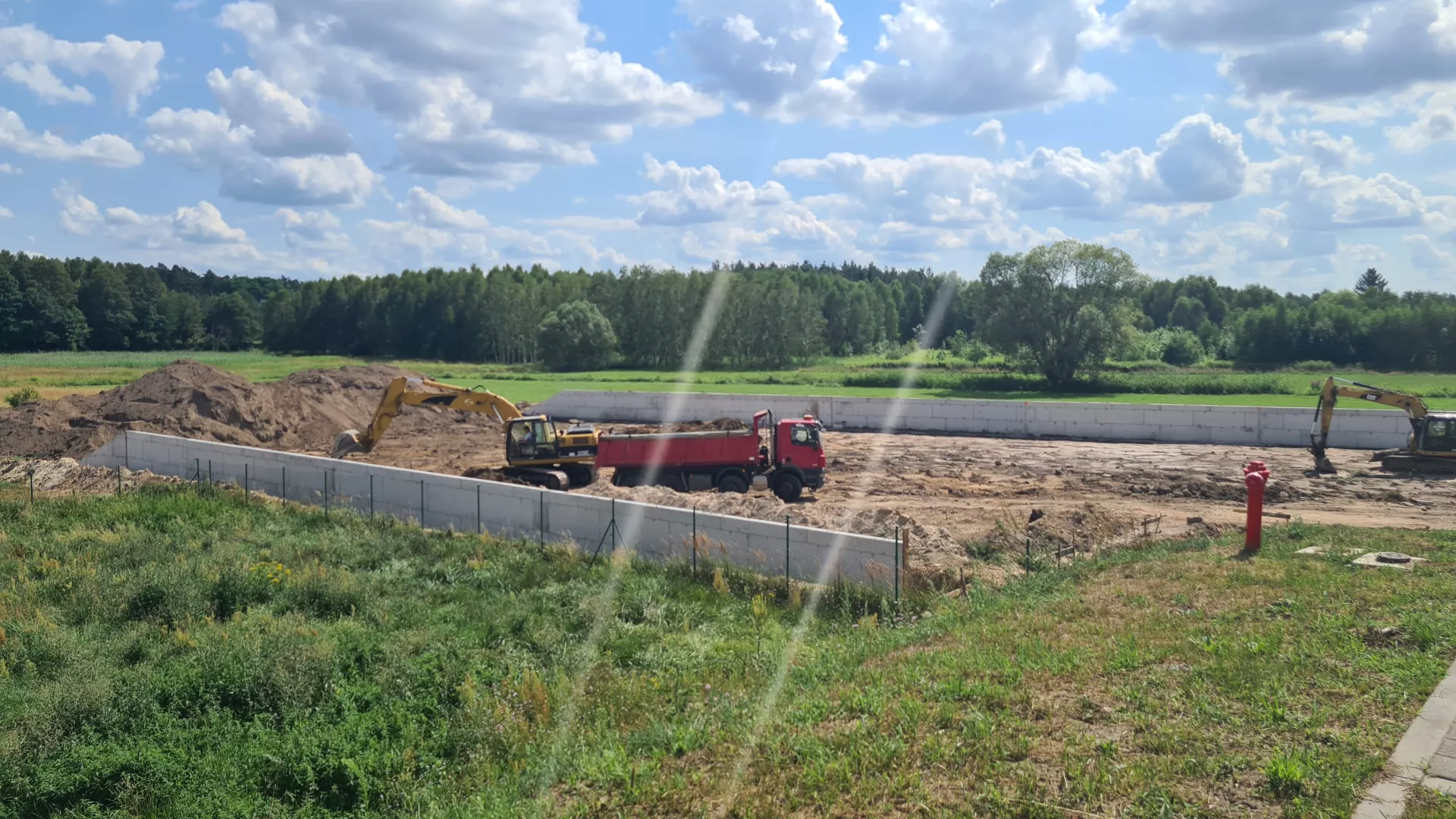 Widok ogólny terenu budowy PSZOK w Lipiu, po wykonaniu dwóch murów oporowych, w trakcie prac ziemnych z użyciem dwóch koparek i wywrotki.