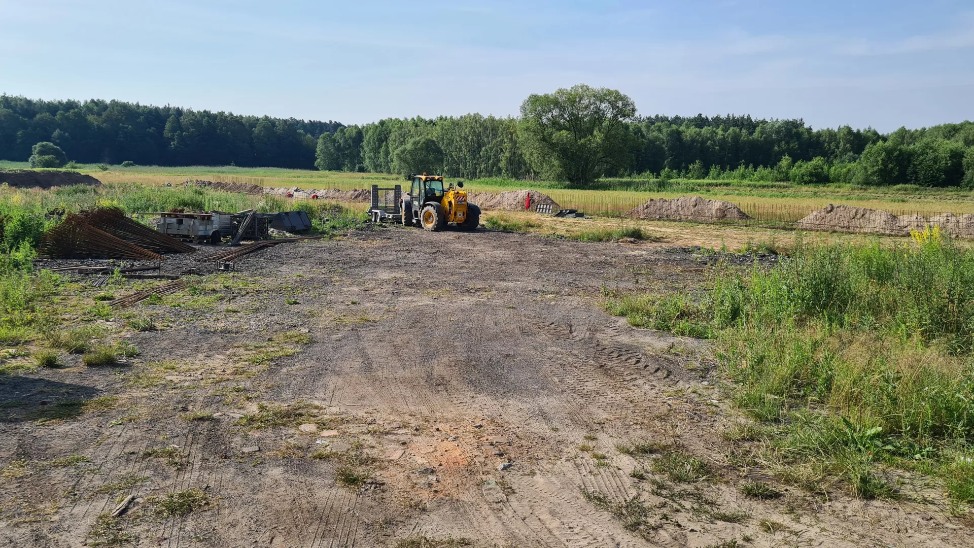 Teren budowy PSZOK w Lipiu jeszcze na wstępnym etapie prac, z widoczną maszyną budowlaną i w tle – zbrojeniem dla muru oporowego.