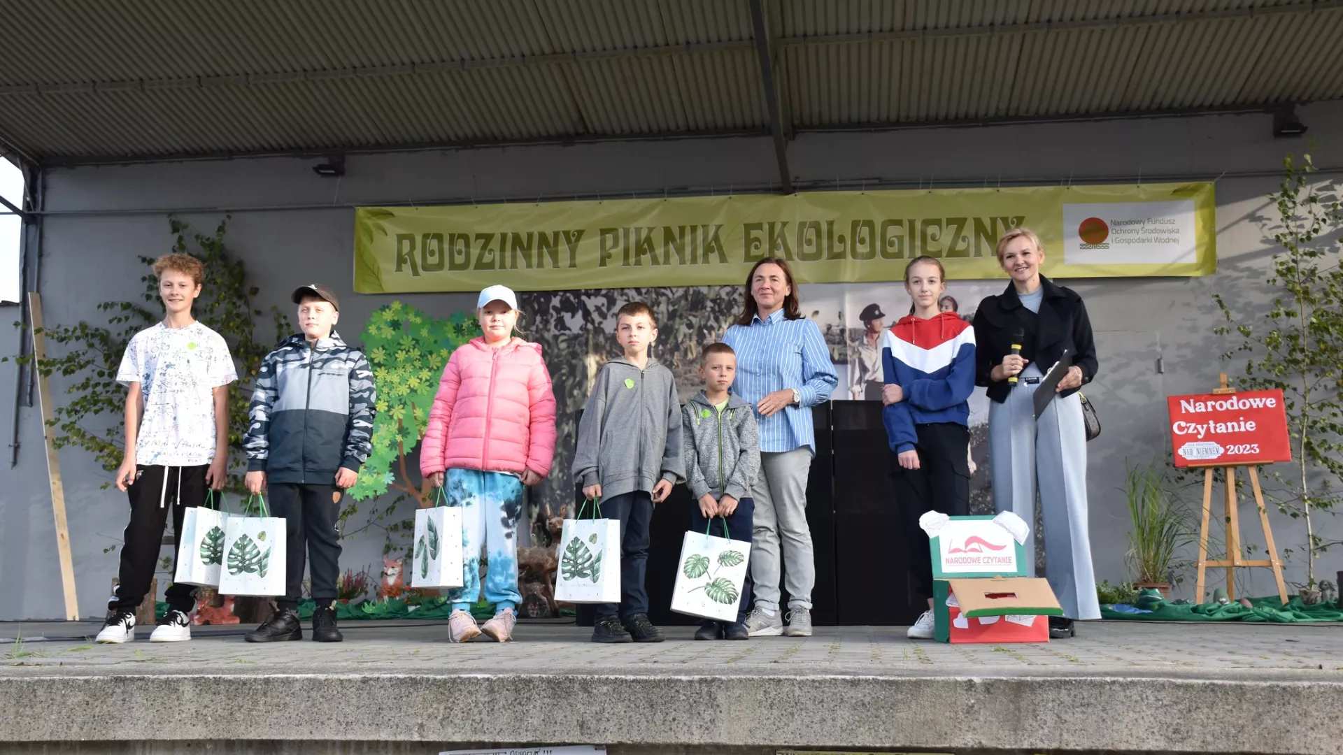 Dzieci szkolne wraz z dyrektor szkoły na scenie pikniku w Parzymiechach.