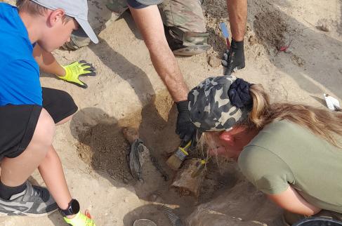 Archeolodzy starannie odsłaniają i wydobywają z ziemi znalezisko.