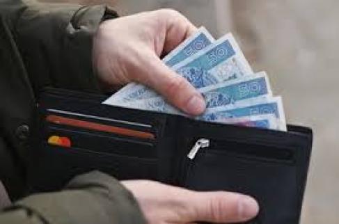 Jedna ręka trzyma portfel druga ręka wyciąga z tego portfela kilka banknotów pięćdziesięciozłotowych. 