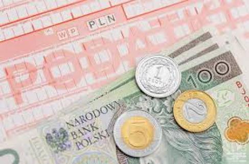 Widoczny blankiet przelewu z napisem podatki oraz leżące na nim trzy banknoty o nominale sto złotych oraz monety o nominale jeden złoty, dwa złote i pięć złotych.